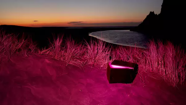 An open capsule on a beach at night. The image has a pink hue.
