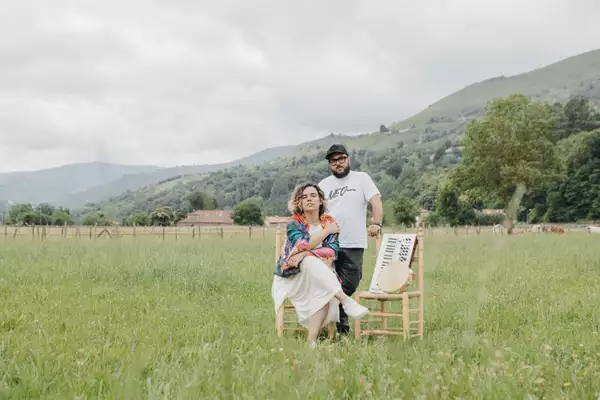 Photo of two members of Casapalma stood in a green field with their instruments