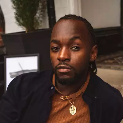 Headshot of Courtney ‘CourtsWrites’ Hayles wearing an orange top and black jacket