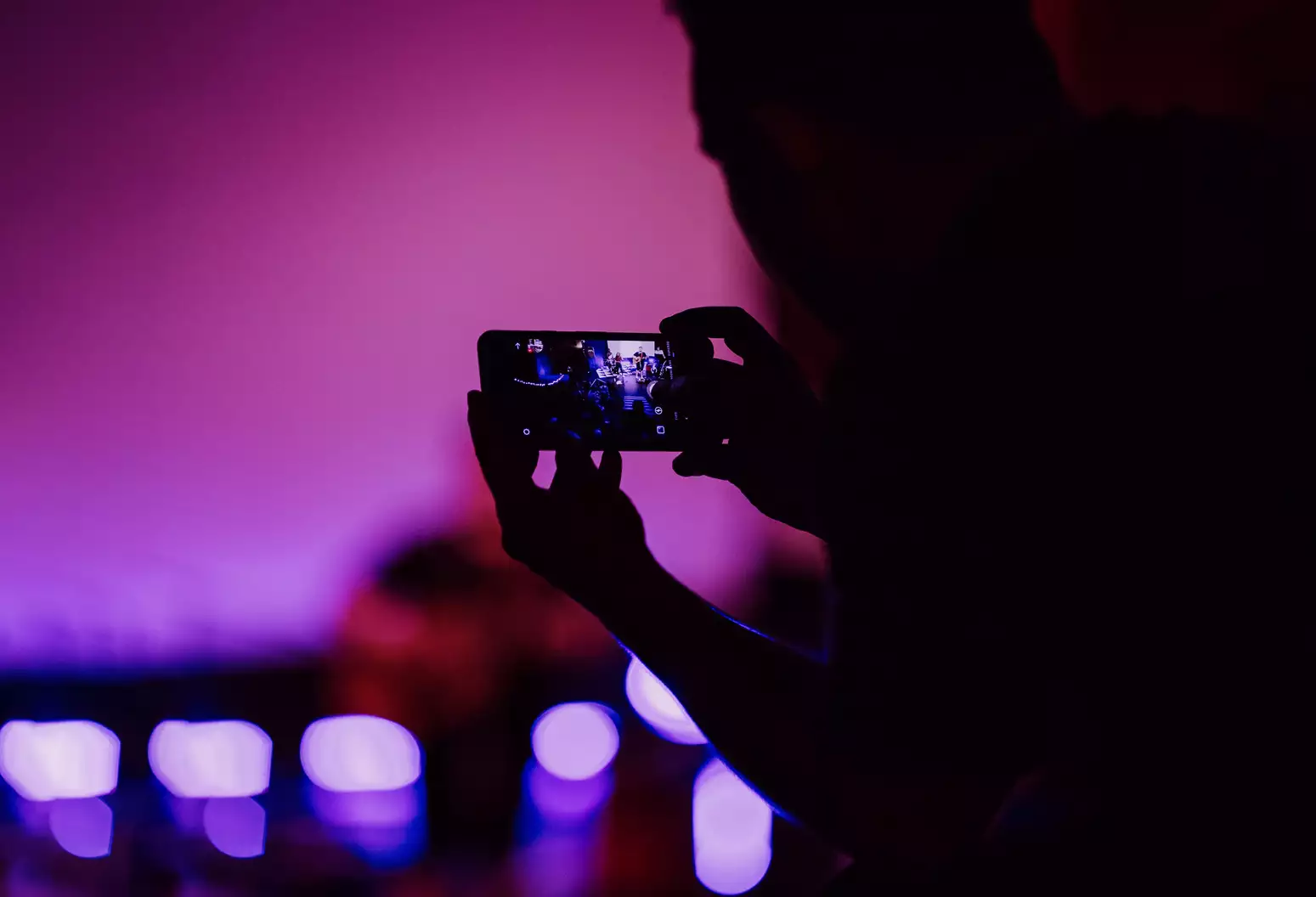 A person takes a picture on their phone at a live event.