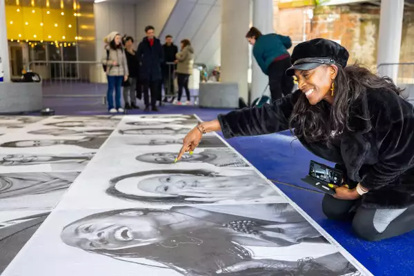 Someone pointing at a black and white portrait of themselves and smiling
