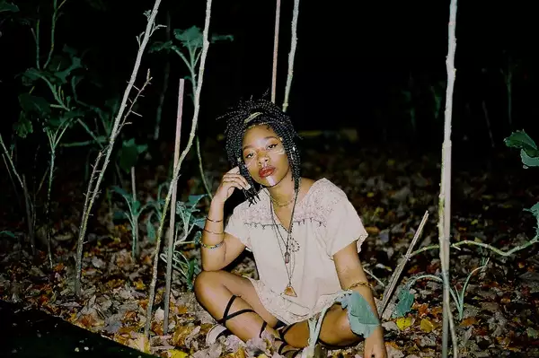 Meduulla - one of the Factory Sounds cohort for 2023 - sits cross legged outdoors among plants at nighttime