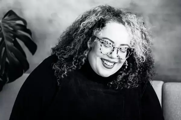 A black and white photograph of Charlotte Barber - one of the Factory Sounds cohort for 2023 - smiling with her eyes closed