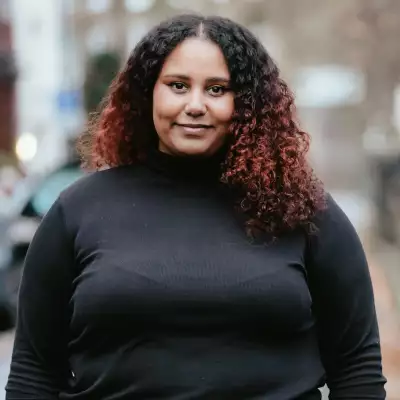 Square headshot of Fauziya Johnson stood outside wearing a black top. The background is blurry.