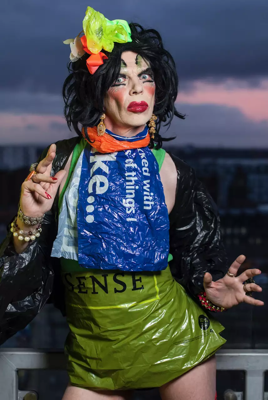 David Hoyle with a black wig, wearing a dress made out of plastic bags