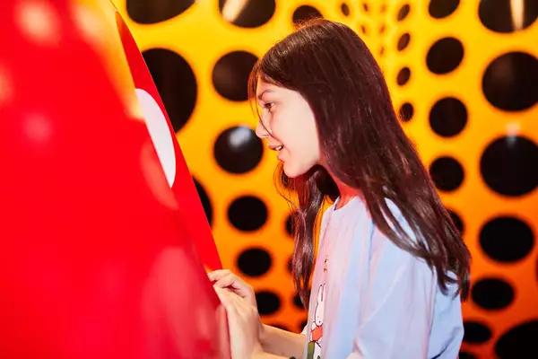 A young girl looks at a Yayoi Kusama artwork