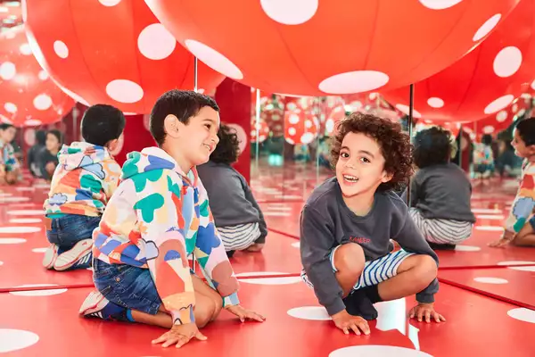 Two young children enjoy a Yayoi Kusama artwork