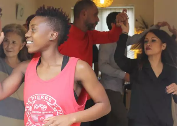Young woman in a doorway with a group of people dancing in the room behind her