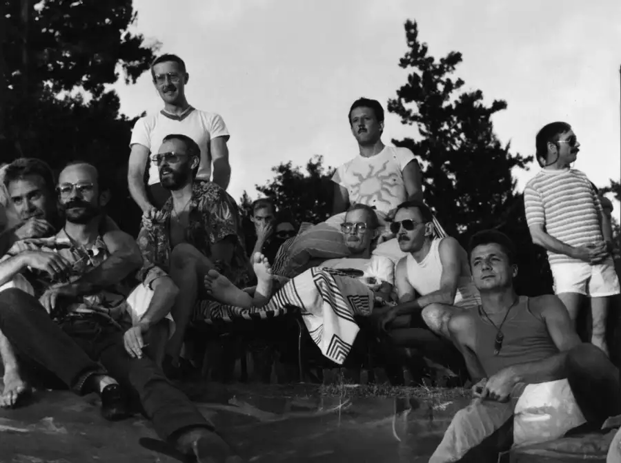 Black and white still from David Weissman's We Were Here, showing a group of men sat outside together