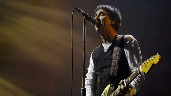 Johnny Marr on stage at Aviva Studios singing into a microphone and playing the guitar