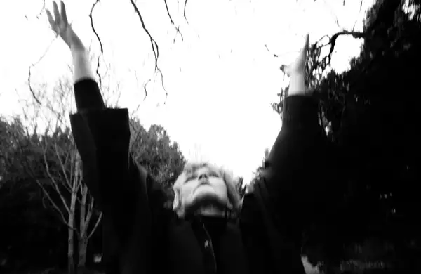 black and white, blurry photo of Maxine Peake looking up at the sky with her hands in the air